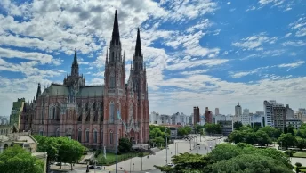 Catedral de La Plata de arquitetura neogótica com suas torres imponentes e detalhadas se erguendo contra um céu azul repleto de nuvens esparsas
